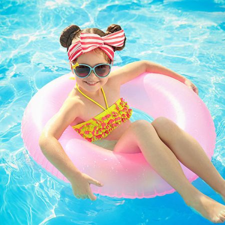 Petite fille sur une bouée rose dans une piscine