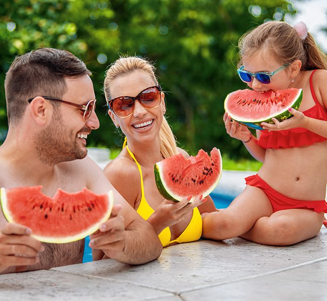 Famille mangeant de la pastèque dans une piscine