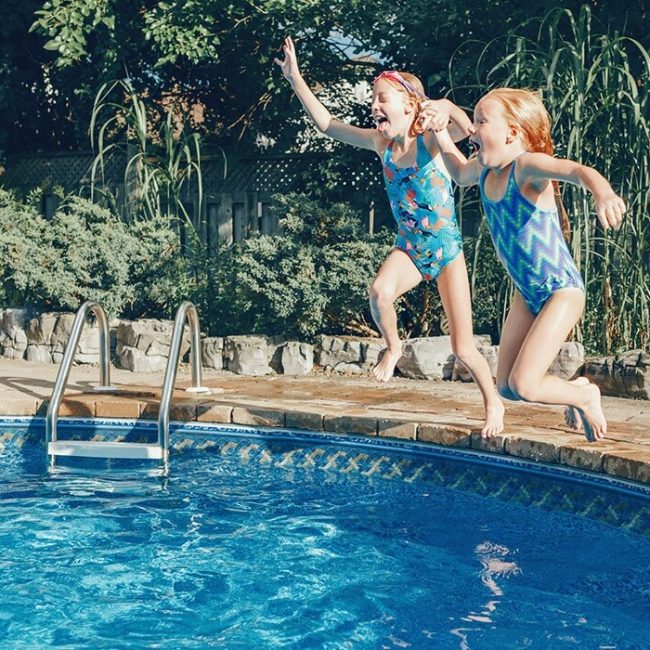 Deux petites filles sautant dans une piscine