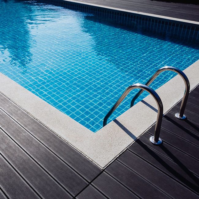 Piscine avec mosaïque et terrasse en bois sombre