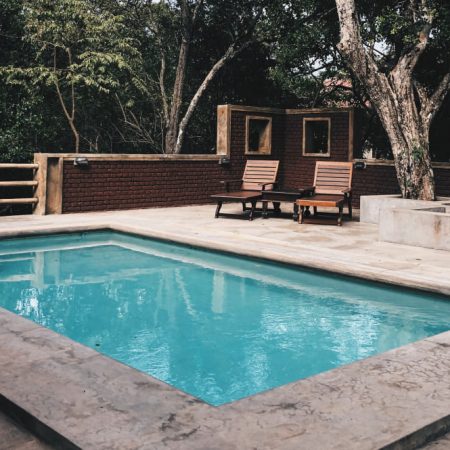 Piscine creusée avec terrasse en béton et chaises en bois