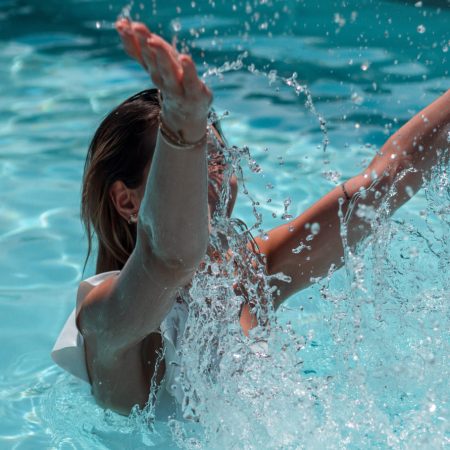 Jeune femme dans une piscine jouant avec l'eau
